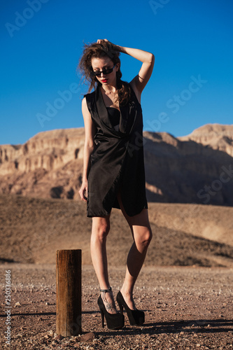 Style fashion sexy girl hitchhiking on the road at desert rocks 
