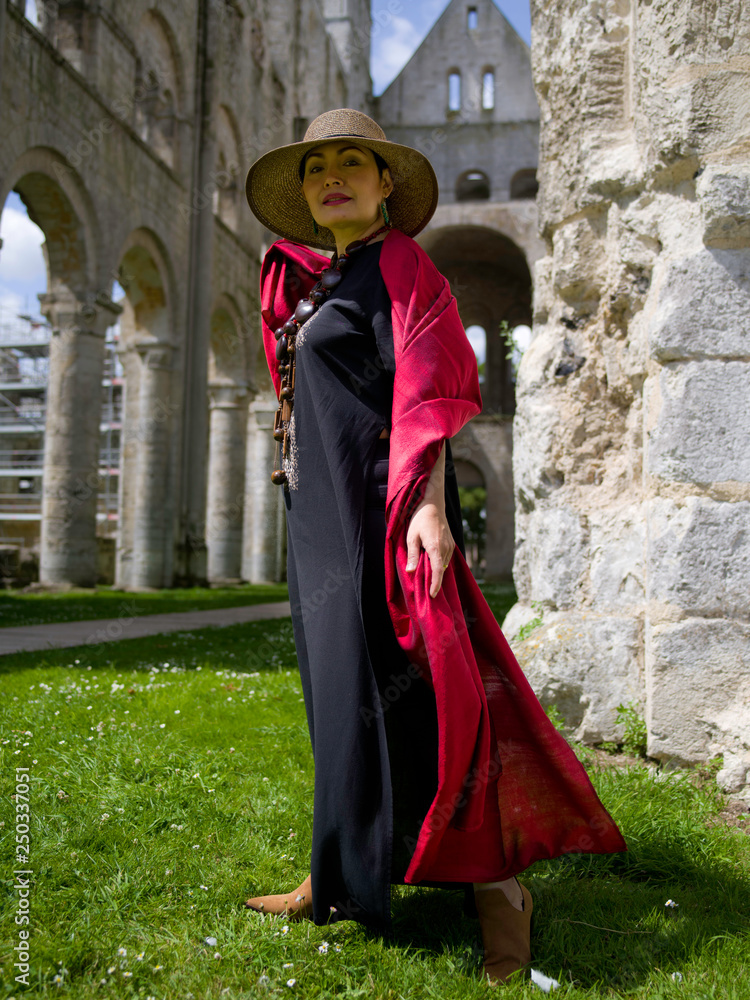 Femme posant une soie rouge dans les ruines d'une église du mayen-âge