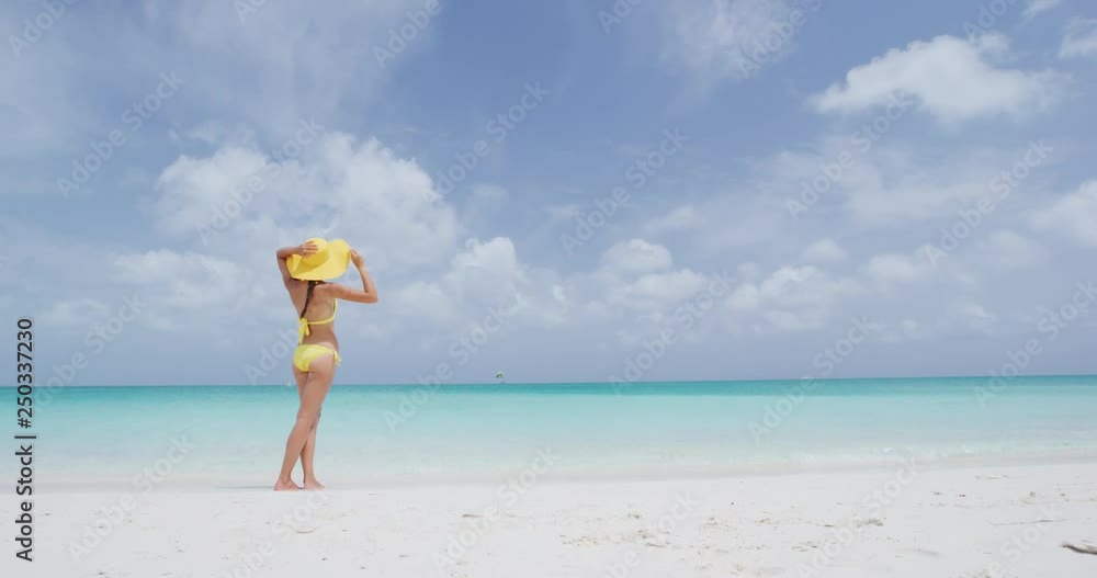 Vacation travel bikini woman on Caribbean beach. Lady with slim sexy body standing on tropical white sand beach in Caribbean looking at perfect turquoise ocean. Luxury destination. Slow motion. Vacation travel bikini woman on Caribbean beach. Lady with slim sexy body standing on tropical white sand beach in Caribbean looking at perfect turquoise ocean. Luxury destination. Slow motion.