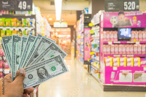A hand holding dollars on shop. A man holding dollars for cash  on product background.Money for sales exchange. Photo concept  finances and money.