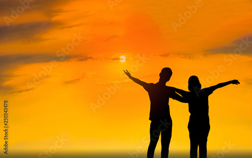 Man and woman in love. They are standing and see the sun set. Woman wearing a hat and man Man hugging woman.Photo concept Silhouette and love. 