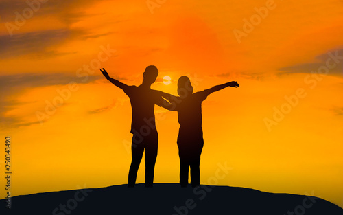 Man and woman in love. They are standing and see the sun set. Woman wearing a hat and man Man hugging woman.Photo concept Silhouette and love. 