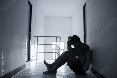 Silhouetted of sad photo. Lonely man sitting on the floor. He is unhappy and sad. He is depression . Photo concept for Disease and depression.