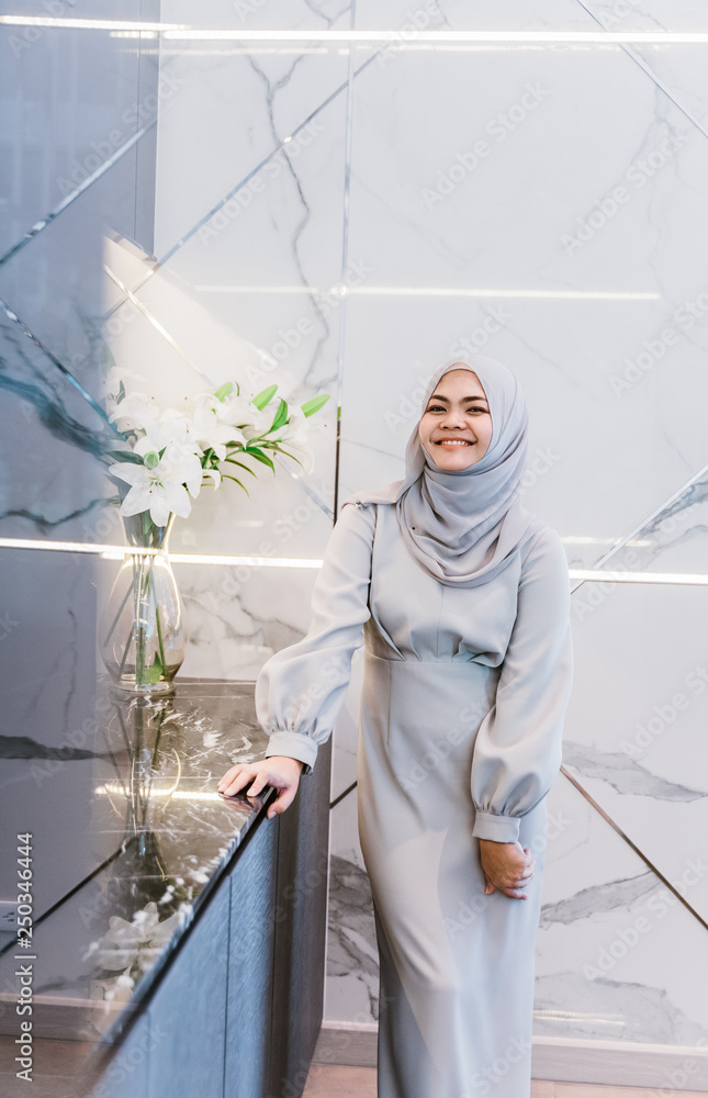 smiling muslim woman standing at kitchen room. happiness woman standing on white modern room. 