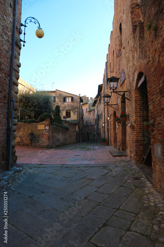 narrow medieval street with lantern on red brick wall in old town of Certaldo tuscany italy photo