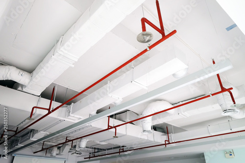 Perspective view of white air duct on the ceiling with red water sprinkler pipe