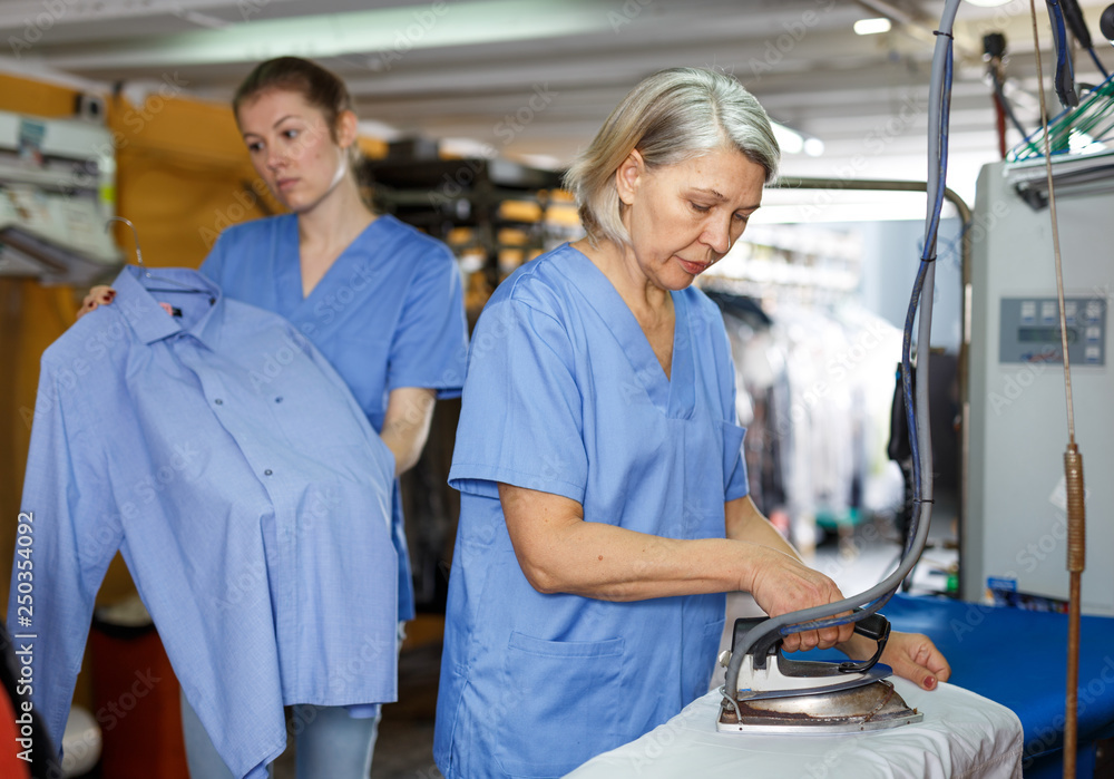 Obraz premium Workers ironing clothes after cleaning