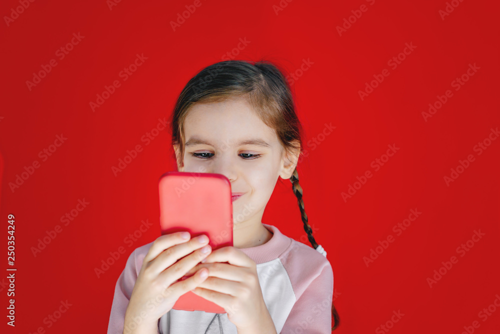 Happy baby girl holding phone on red background. Happy baby girl holding phone on red background.