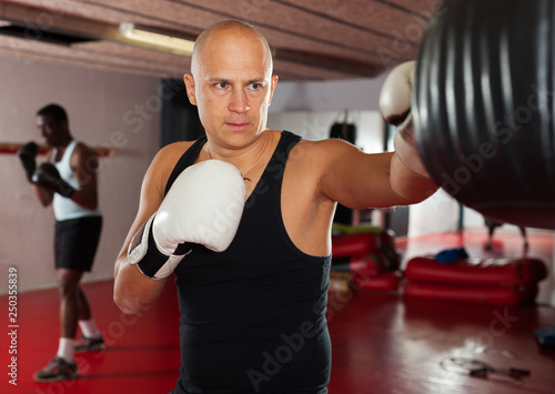 Confident boxer man training on punching bag