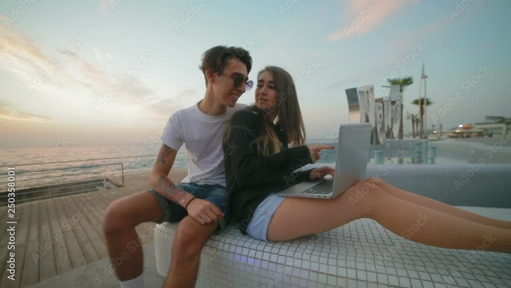 slow motion pretty brunette girl in black jumper types on laptop and guy in sunglasses nods against summer sunset slow motion pretty brunette girl in black jumper types on laptop and guy in sunglasses nods against summer sunset