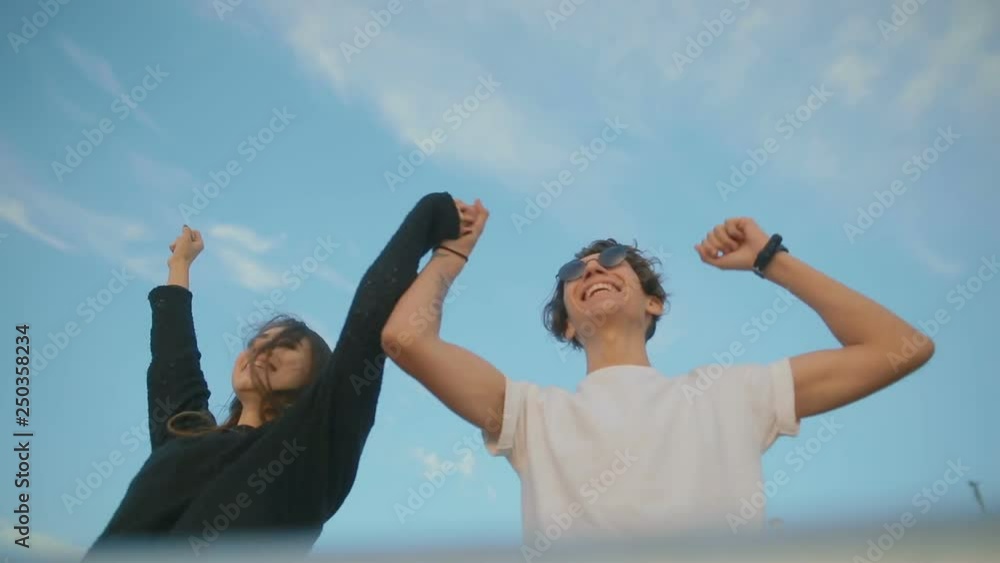 low angle shot slow motion couple runs to boardwalk edge and raises joined hands intensively at metal railing low angle shot slow motion couple runs to boardwalk edge and raises joined hands intensively at metal railing