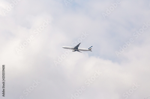 An airplane flying in the blue sky. passenger plane flies highly over clouds of aerosphere. airplane flying in a clear pale blue sky. An airplane taking off at airport. © kanpisut