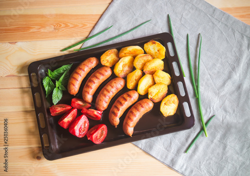 Griled pork  sausages, roasted potatoes and fresh tomatoes. Top view. photo