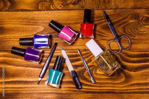 Different manicure tools and nail polishes on wooden table. Top view