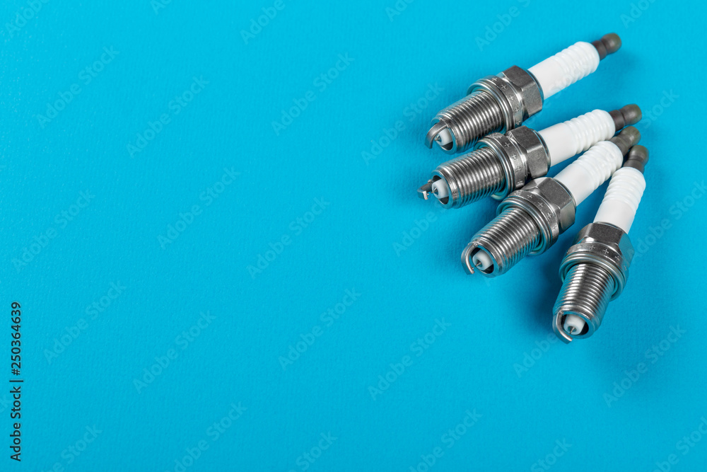 A set of new spark plugs a blue background. A set of new spark plugs a blue background.