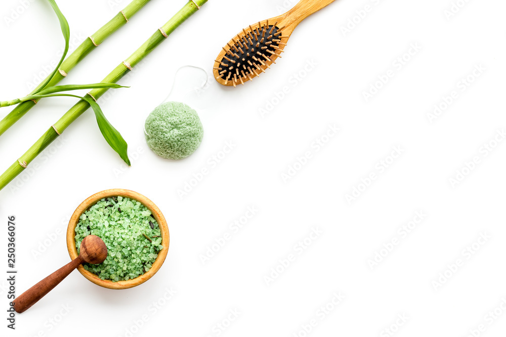 Asian spa treatment concept with natural ingredients. Spa salt, lotion, sponge near bamboo on white background top view copy space Asian spa treatment concept with natural ingredients. Spa salt, lotion, sponge near bamboo on white background top view copy space