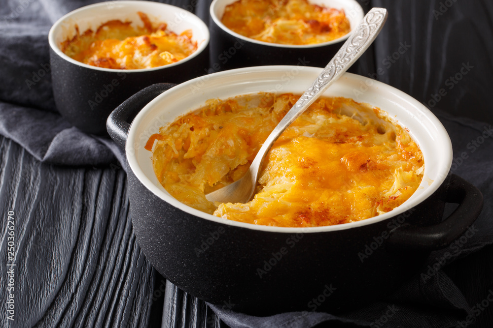 Golden delicious gratin made of potatoes, sour cream, onions and cheddar cheese close-up in a pan. horizontal Golden delicious gratin made of potatoes, sour cream, onions and cheddar cheese close-up in a pan. horizontal