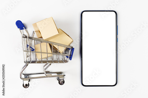 Supermarket trolley with boxes on white background. Mockup smartphone with blank screen, can be add your texts or others.