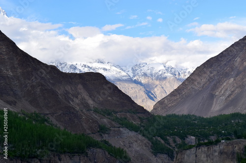 View over the hill with mountain trail and snowy mountains on the background. Beautiful mountain trail landscape.