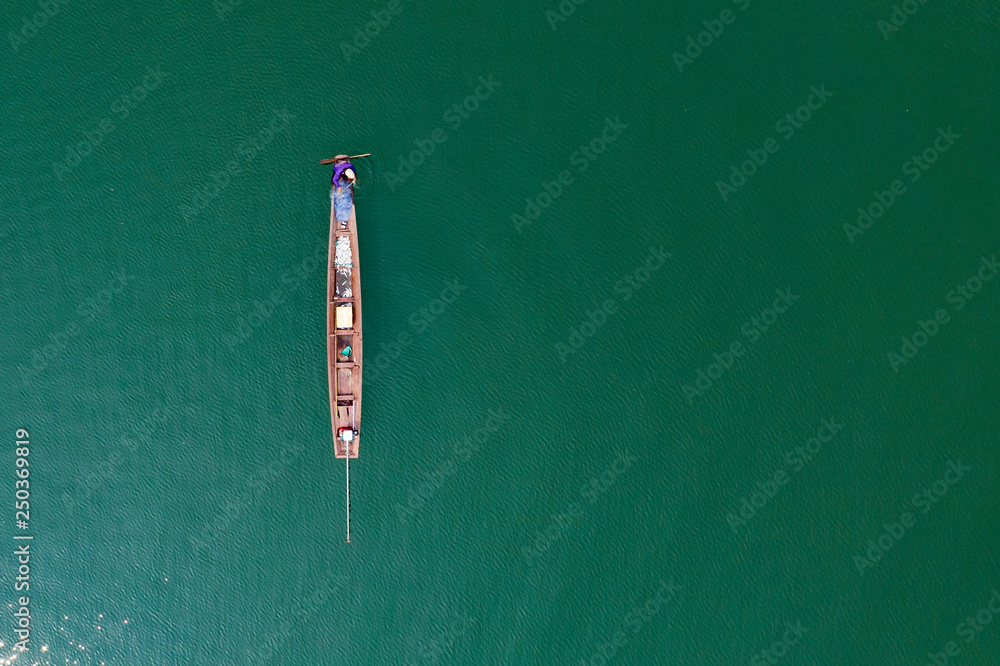 (View from above) Stunning aerial view of a traditional long-tail boat with a local person who is fishing in the waters of the Nam Ngum Reservoir, Thalat, northern Laos.