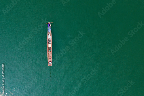 (View from above) Stunning aerial view of a traditional long-tail boat with a local person who is fishing in the waters of the Nam Ngum Reservoir, Thalat, northern Laos.