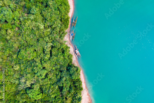 (View from above) Stunning aerial view of a a green coast of a tropical island with some traditional fishing boats in Nam Ngum Reservoir, Thalat, northern Laos. photo