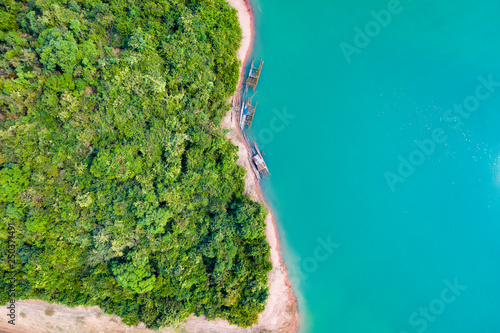 (View from above) Stunning aerial view of a a green coast of a tropical island with some traditional fishing boats in Nam Ngum Reservoir, Thalat, northern Laos.