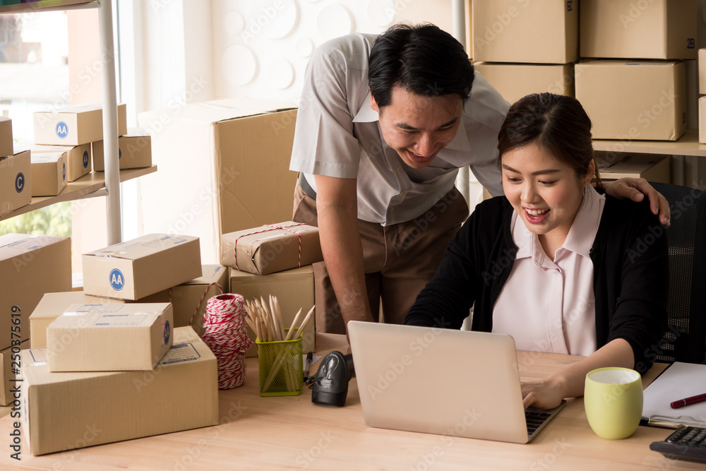 Happy couple success in their owner small business online with package box. Male and female are looking their orders on laptop computer. Happy couple success in their owner small business online with package box. Male and female are looking their orders on laptop computer.