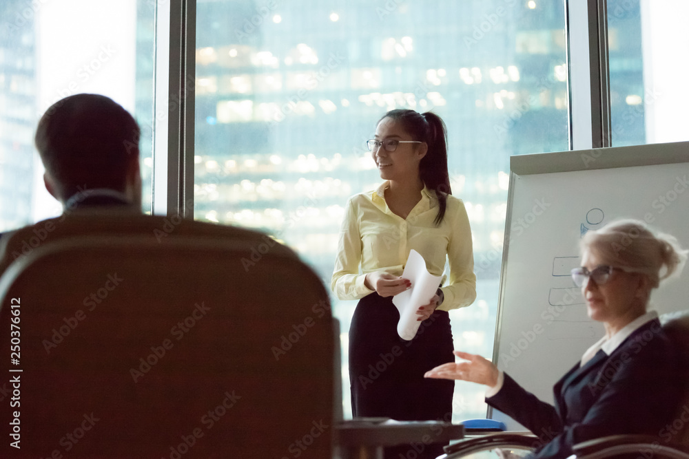 Smiling asian corporate manager giving flip chart presentation in office Smiling asian corporate manager giving flip chart presentation in office