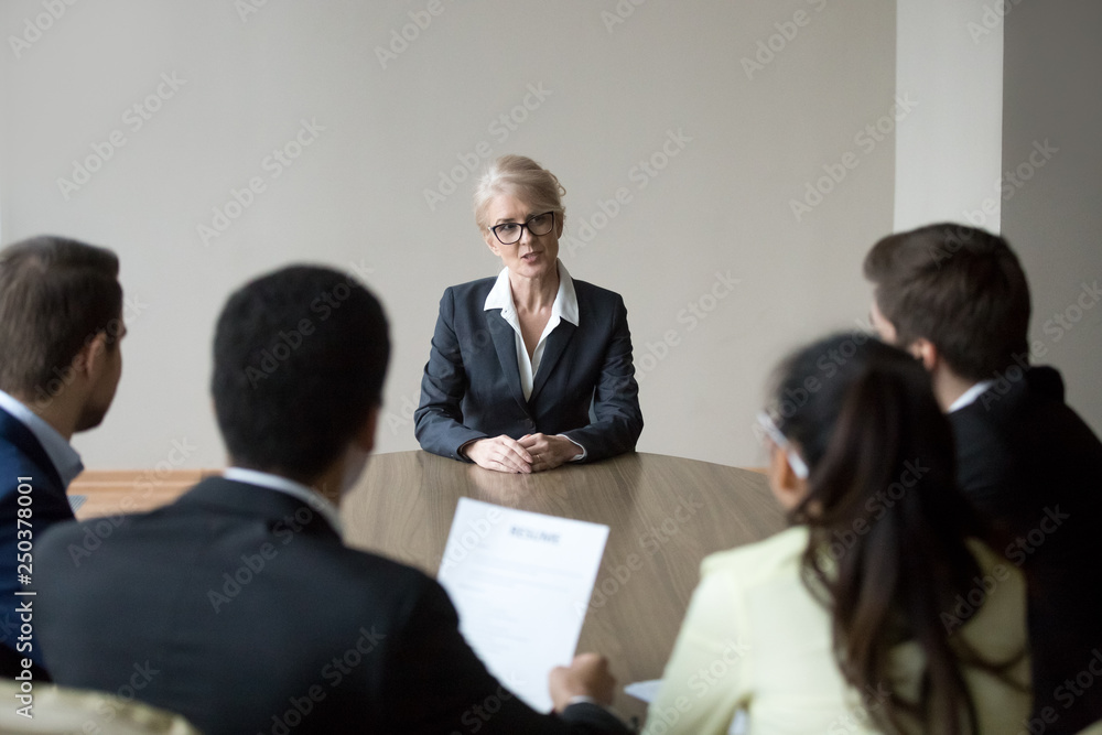 Middle-aged confident applicant talking to hr managers during job interview Middle-aged confident applicant talking to hr managers during job interview