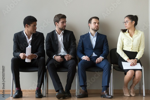 Diverse male applicants looking at female rival waiting for interview