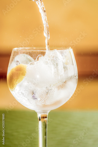 Coctel gintonic de gin con chorro y salpicaduras de la tónica, twist de limón y hielo