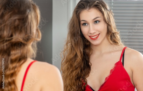young smiling woman putting makeup in the mirror