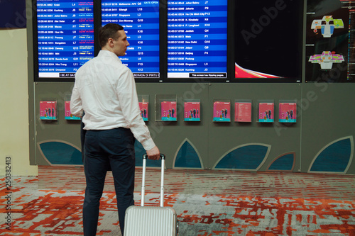 man in airport searching gate number using information screen  photo