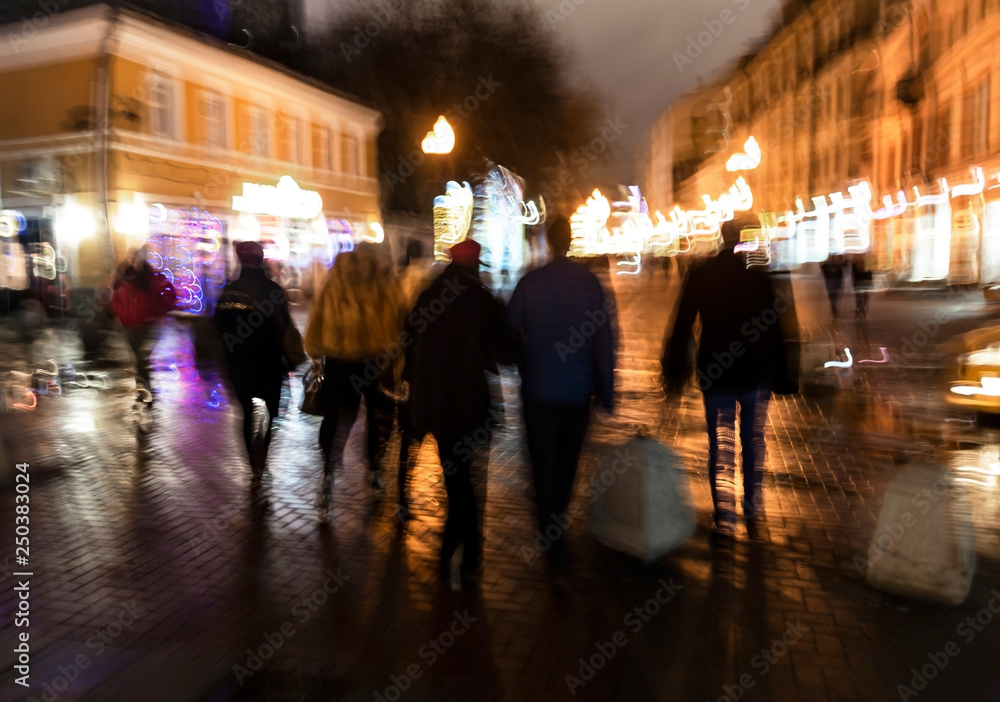 People in the evening are on the streets of the city. Intentional motion blur.