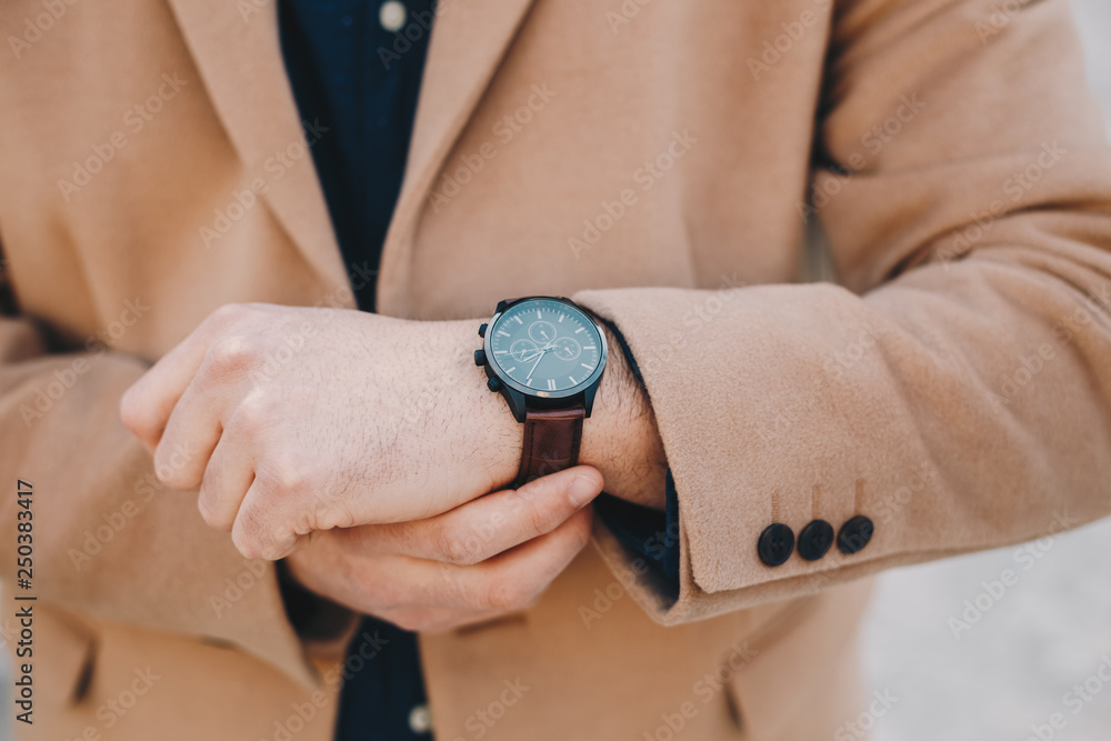 Close up detail of men's fashion accessory - a man checking the time and fixing the belt on his wrist watch. Close up detail of men's fashion accessory - a man checking the time and fixing the belt on his wrist watch.