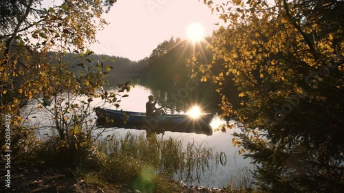 Woman with canoe paddling on calm lake at sunset