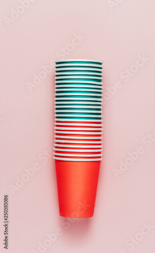 Tower stack of paper cups on pink background. Red and green colors. Top view, flat lay.