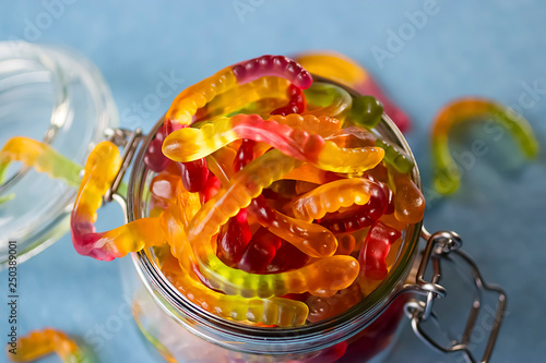 Chewing marmalade in the form of worms in a glass jar. Gummies.