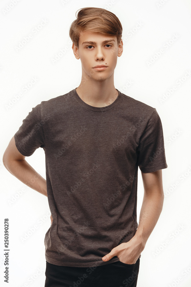 Isolated studio portrait handsome Caucasian male model dressed in casual t-shirt looking at camera and standing indoors against studio white background. Isolated studio portrait handsome Caucasian male model dressed in casual t-shirt looking at camera and standing indoors against studio white background.