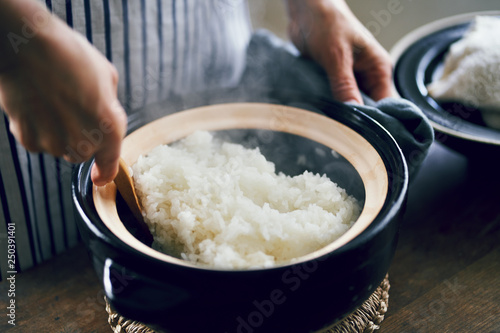 土鍋で炊いたご飯をかき混ぜる女性 photo