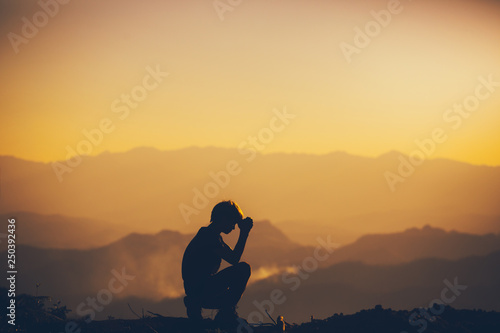 Fotografie, Obraz Man sitting praying and worshipping God at sunset background
