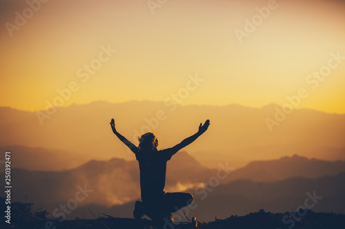 Man sitting and lift two hands for worshipping God at sunset background. christian silhouette concept.