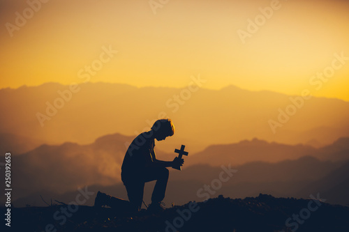 Photos Young man sitting down and praying to God at sunset background