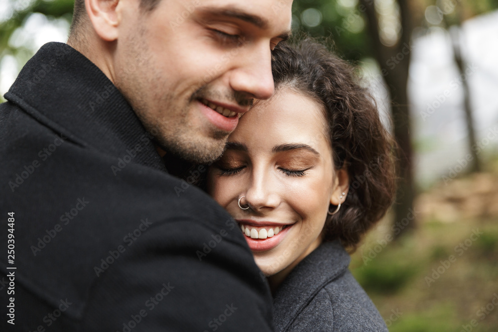 Portrait closeup of happy people man and woman 20s hugging, while walking through green park Portrait closeup of happy people man and woman 20s hugging, while walking through green park