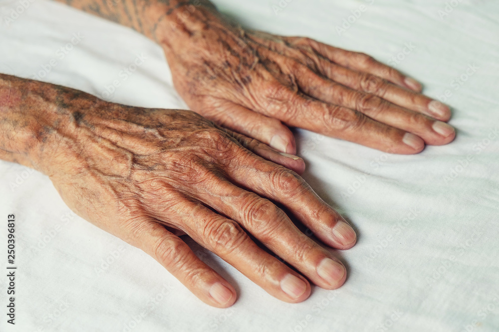 Fototapeta premium Hands of an old man on the wood table .vintage tone