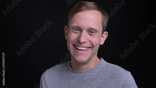 Closeup portrait of young attractive caucasian man turning rto camera and laughing happily with background isolated on black photo