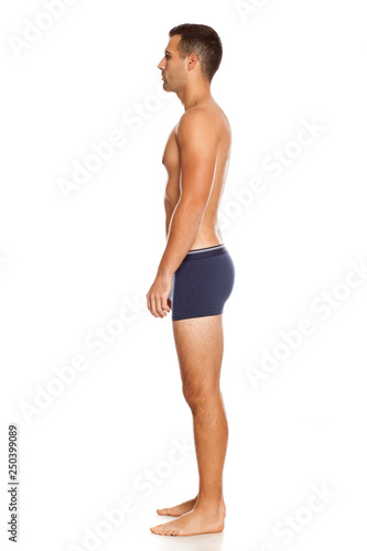 Profile od shirtless handsome man in panties on white background