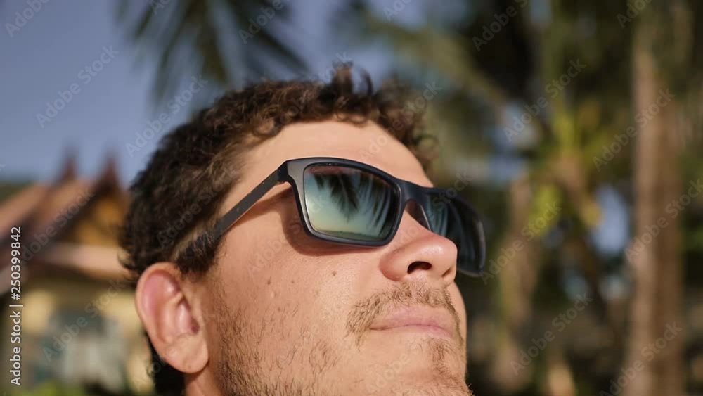 Handsome young man in sunglasses looks at the sea Handsome young man in sunglasses looks at the sea