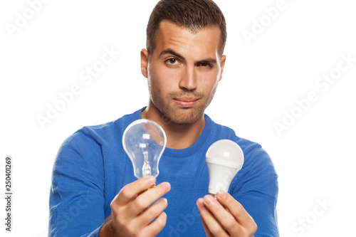 portrait of young man, holding LED bulb and old fachion bulb on white background